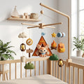 Handmade felt baby mobile featuring a fox in a tent, campfire, compass, and camping gear hanging from a wooden frame over a baby crib, adventure-themed nursery decor