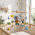 Handmade felt baby mobile featuring a central elephant wearing a vest, surrounded by lotus flowers, fish, pond plants, and raindrops hanging from a wooden frame over a baby crib, pond-themed nursery decor.