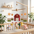Handmade personalized felt baby mobile featuring farm animals like a cow, pig, chicken, and rooster with a red barn labeled 'OWEN' hanging from a wooden frame over a baby crib, farm-themed nursery decor