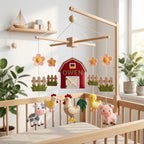 Handmade personalized felt baby mobile featuring farm animals like a cow, pig, chicken, and rooster with a red barn labeled 'OWEN' hanging from a wooden frame over a baby crib, farm-themed nursery decor