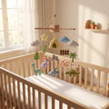Handmade felt baby mobile featuring various dinosaurs, rocky mountains, palm trees, and clouds hanging over a wooden baby crib, dinosaur themed nursery decor