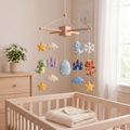 Handmade felt baby mobile featuring dragons, castles, and a dragon egg hanging over a wooden baby crib, fantasy-themed nursery decor