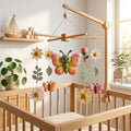 Handmade felt butterfly baby mobile with daisies, flowers and leaves hanging above a wooden crib in a floral nursery.