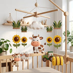 Handmade felt farm baby mobile with a cow, calf, sheep, sunflowers, tractor and hay bale hanging above a wooden crib.