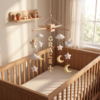 Personalized felt baby mobile with an angel, dove, stars, and moon hanging over a wooden crib, featuring the name 'GRACE' in the center.