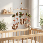 Handmade felt woodland baby mobile with a fox, deer, squirrel, owl and bunny hanging above a wooden crib.