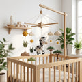 Handmade felt zebra baby mobile with safari trees, clouds, sunshine and flowers hanging above a wooden crib.