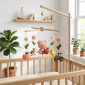 Handmade felt pig baby mobile with pig, apple, cow, chick, pumpkin, flowers and tractor hanging above a wooden crib.