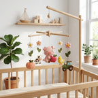 Handmade felt pig baby mobile with pig, apple, cow, chick, pumpkin, flowers and tractor hanging above a wooden crib.