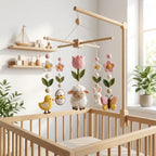 Handmade felt spring baby mobile with lamb, bunny, chick, butterfly, tulip, flowers and Easter egg hanging above a wooden crib.