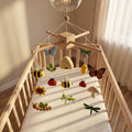 Handmade felt baby mobile featuring various garden insects, bees, butterflies, and flowers hanging over a wooden baby crib, nature-themed nursery decor