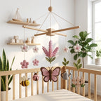 Handmade felt lavender butterfly baby mobile with bee, ladybug, flowers, watering can, and garden fence hanging above a wooden crib.