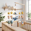 Personalized felt airplane baby mobile with hot air balloons, helicopter, rocket and stars hanging above a wooden crib.