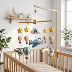Personalized felt airplane baby mobile with hot air balloons, helicopter, rocket and stars hanging above a wooden crib.