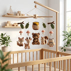 Personalized felt woodland baby mobile with a bear, fox, deer, squirrel, owl and honey pot hanging above a wooden crib.